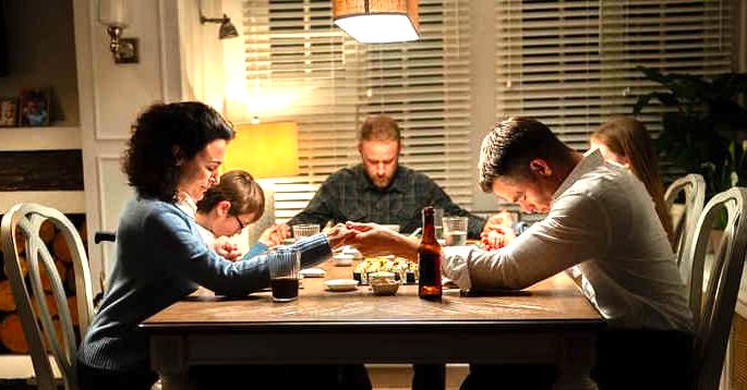 Familia rezando em volta da mesa de jantar