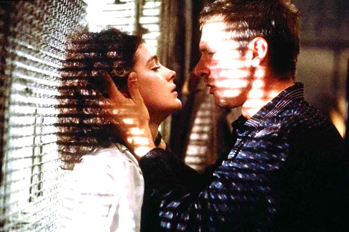 Deckar e Rachel prestes a se beijar em janela que exibe a luz entrando pela grade