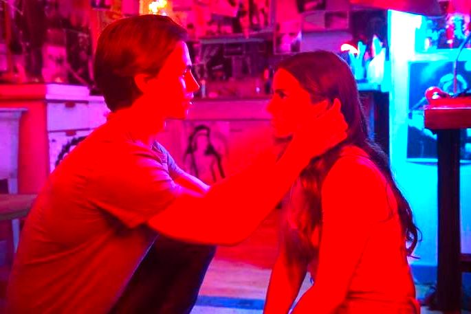casal jovem, frente a frente, sentados no chão de uma sala vermelha