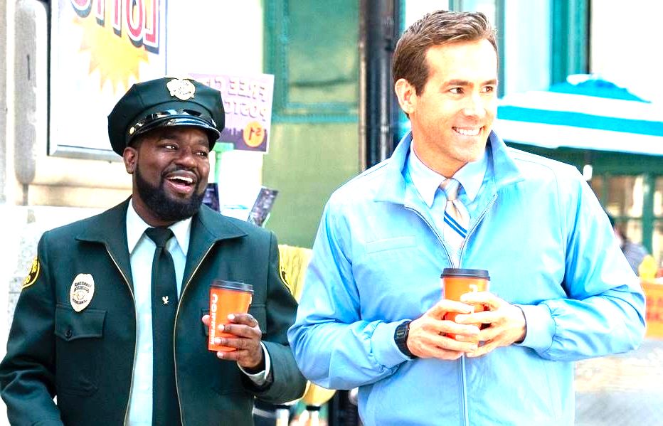 cena do filme Free Guy mostra um homem branco e um policial negro caminhando na rua