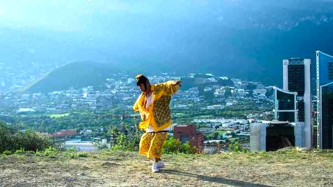 filme mexicano Ha no estou aquí. Jovem mexicano com roupas coloridas dança em lugar ao ar livre com vista da cidade ao fundo