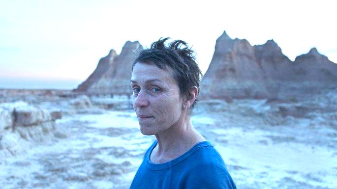 Mulher de cabelos curtos e blusa azul, com deserto e montanhas ao fundo