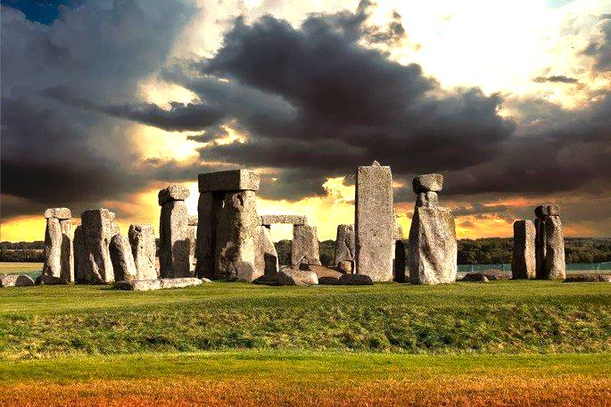 monumento de pedras feito no período neolítico. Pedras dispostas em campo verde com nuvens negras no céu